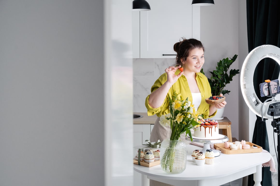 Content young female blogger filming video during cake preparation